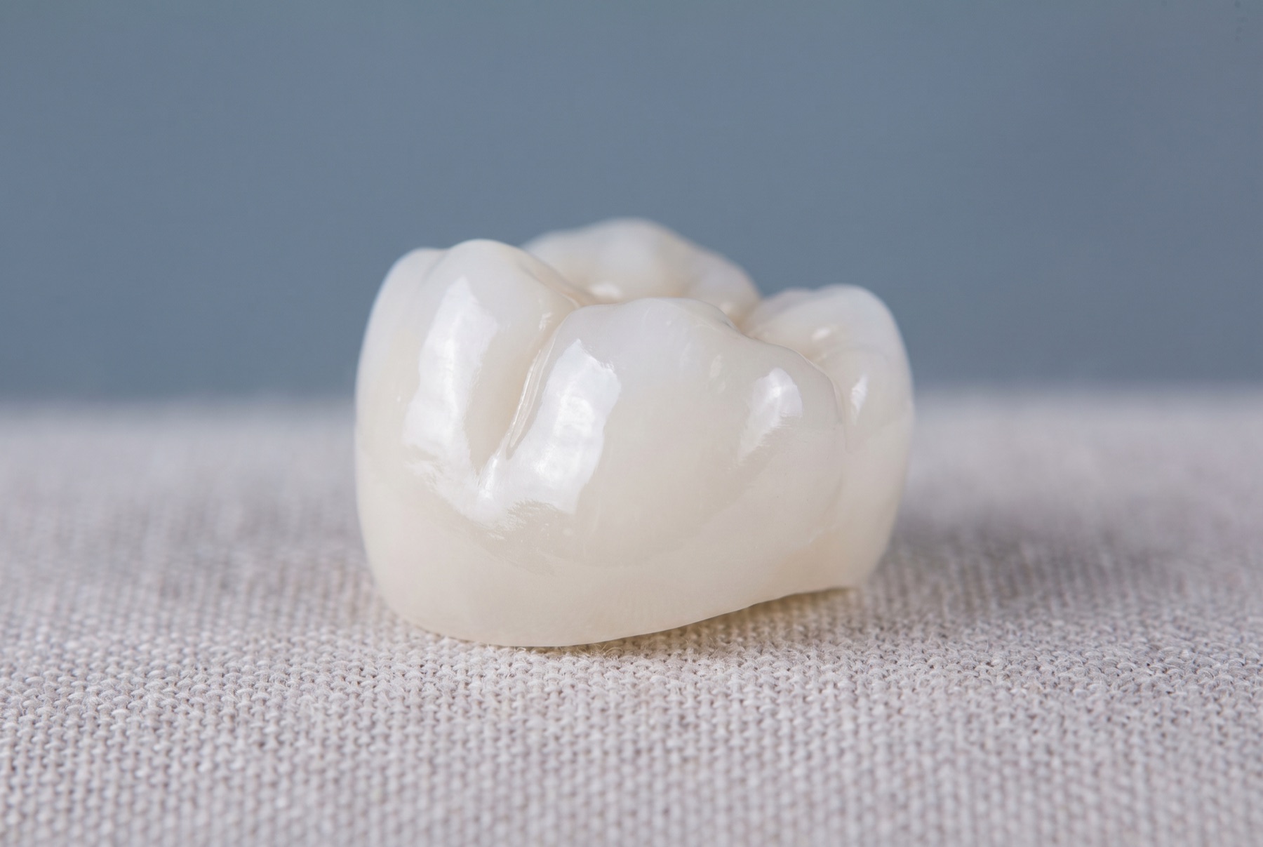 A glossy white ceramic dental crown