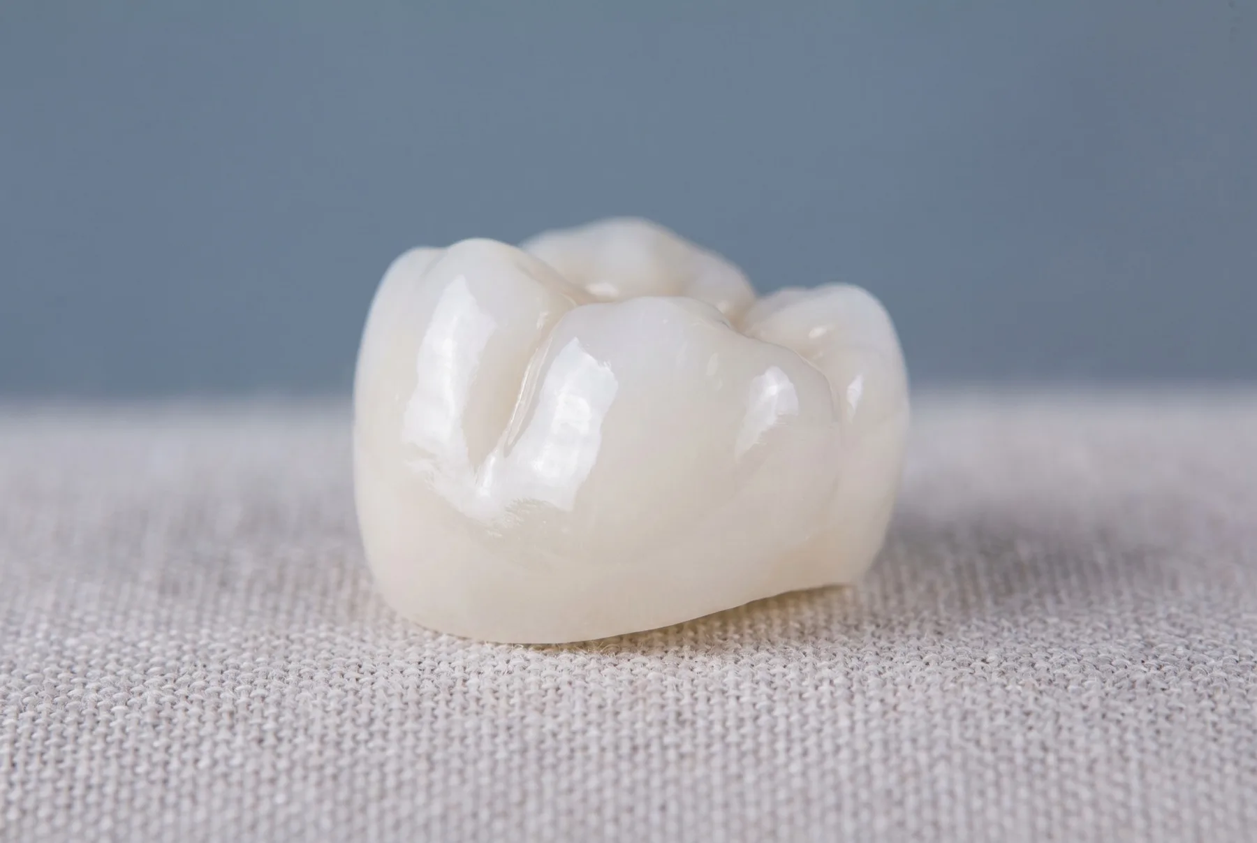 A glossy white ceramic dental crown